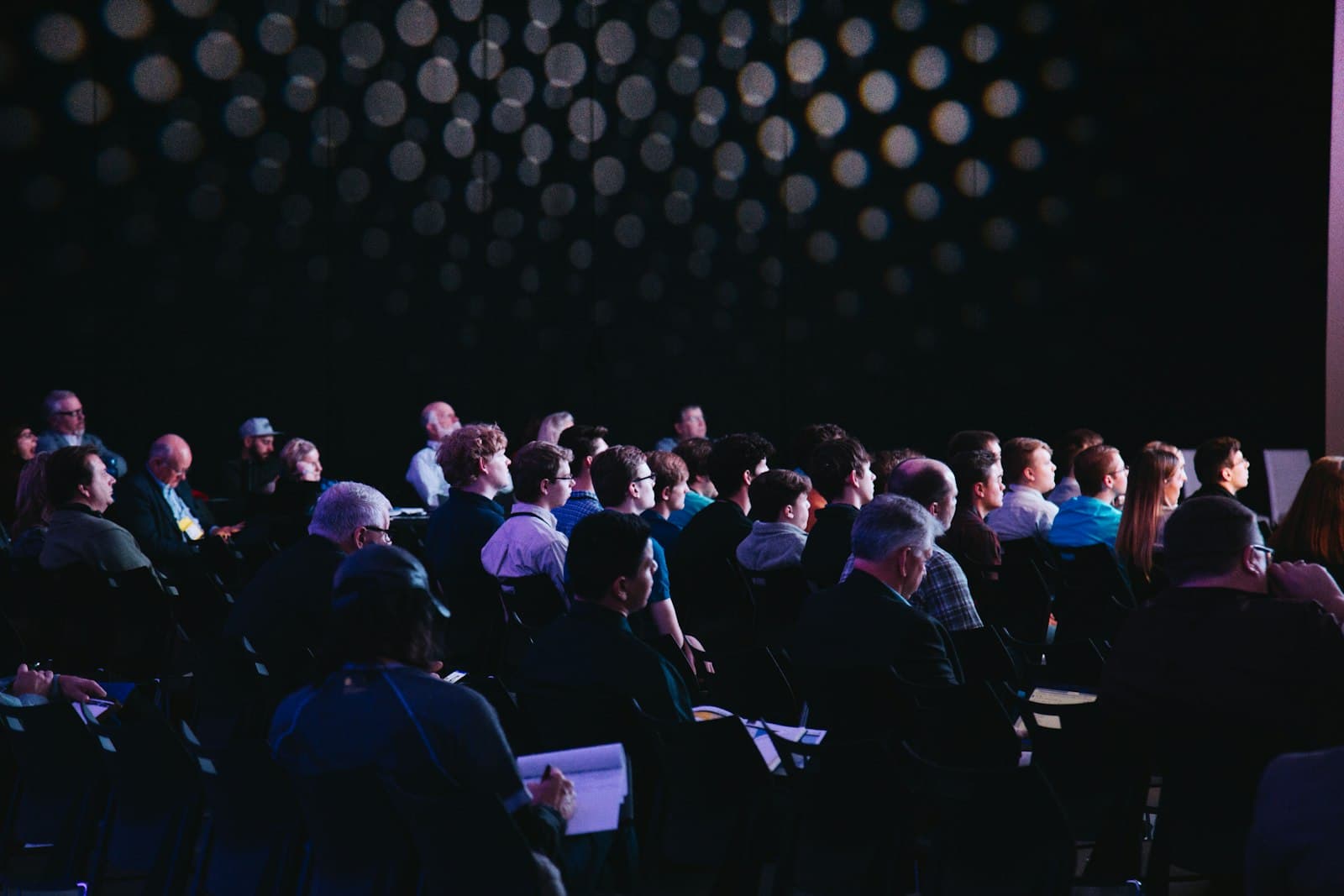 Audience at a professional conference summit with stage lighting